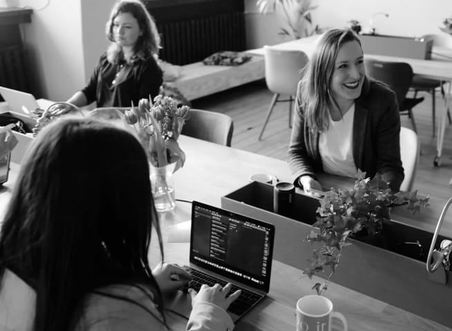 Three women sitting at a desk.