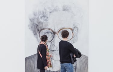 Two people looking at a photo of a man wearing glasses.